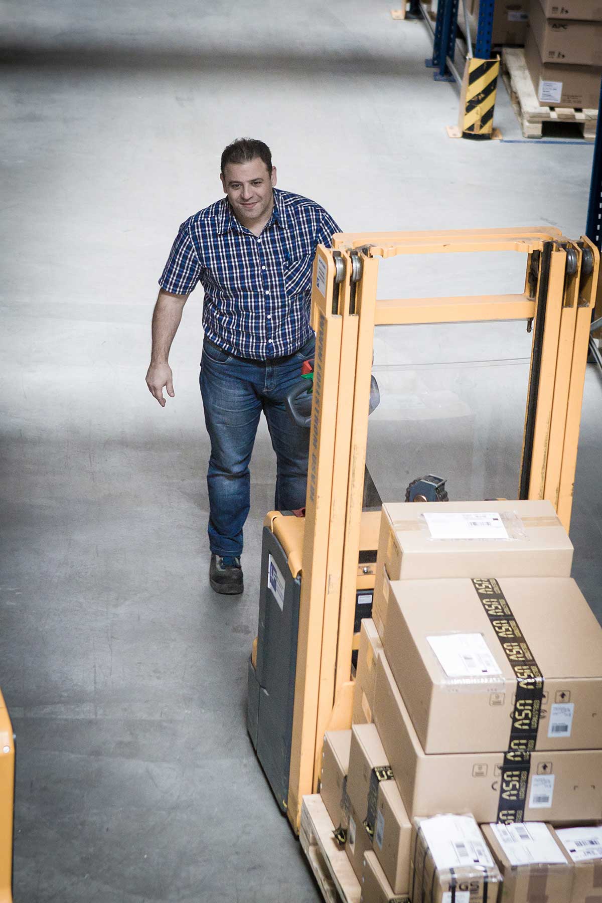 Dario Tosto, Lagerist bei multimatic EDELSTROM GmbH, mit einem Hubwagen im Lager